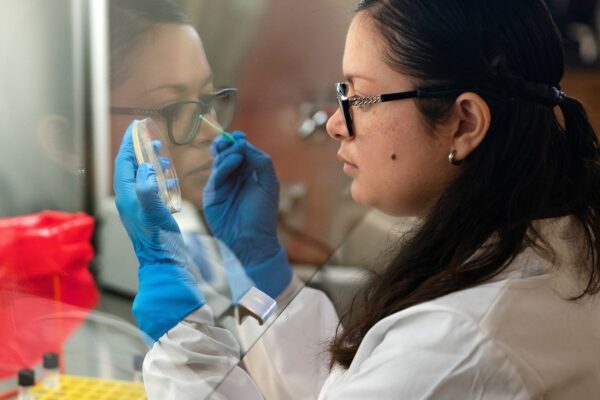 Woman in glasses inspecting petri dish