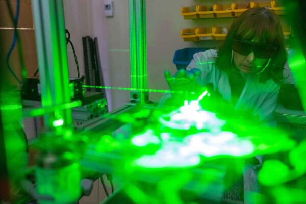 researcher in protective glasses looking at a green electron beam