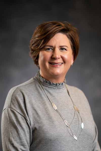 Portrait of short-hair woman in sweater and silver necklace smiling